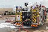 A fire truck surrounded by foam and water.