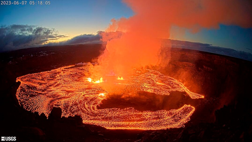 Orange smoke rising from lava in volcano crater.