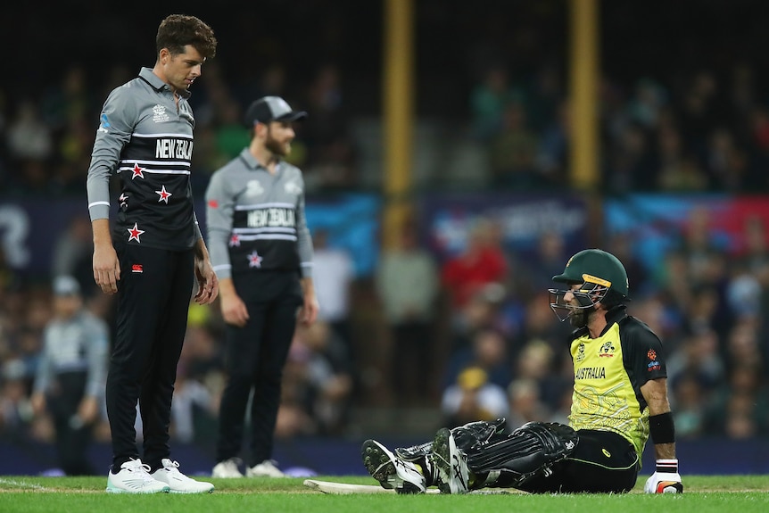 Glenn Maxwell sits on the ground as Mitch Santner looks on