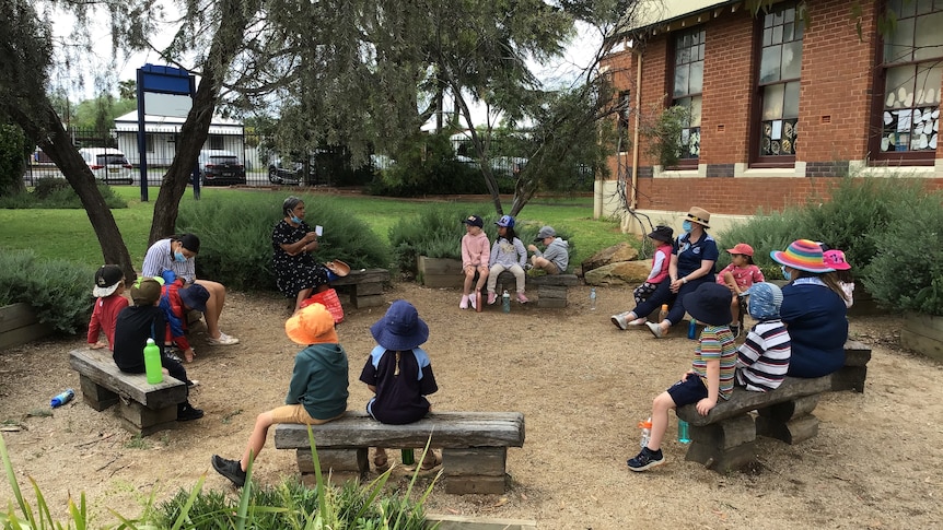 Children are outside sitting done and learning 