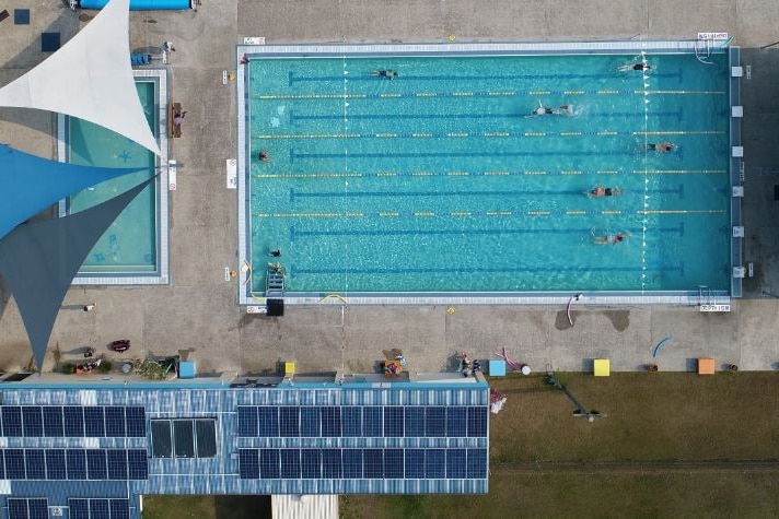 aerial view of an outdoor lap pool which has covered seating with solar panels on the roof