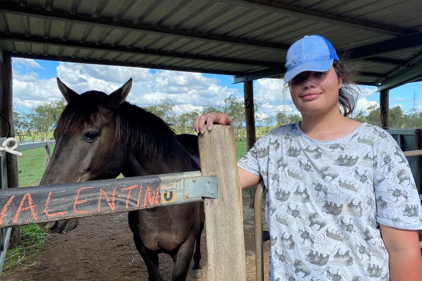 Teenage boy stands next to horse