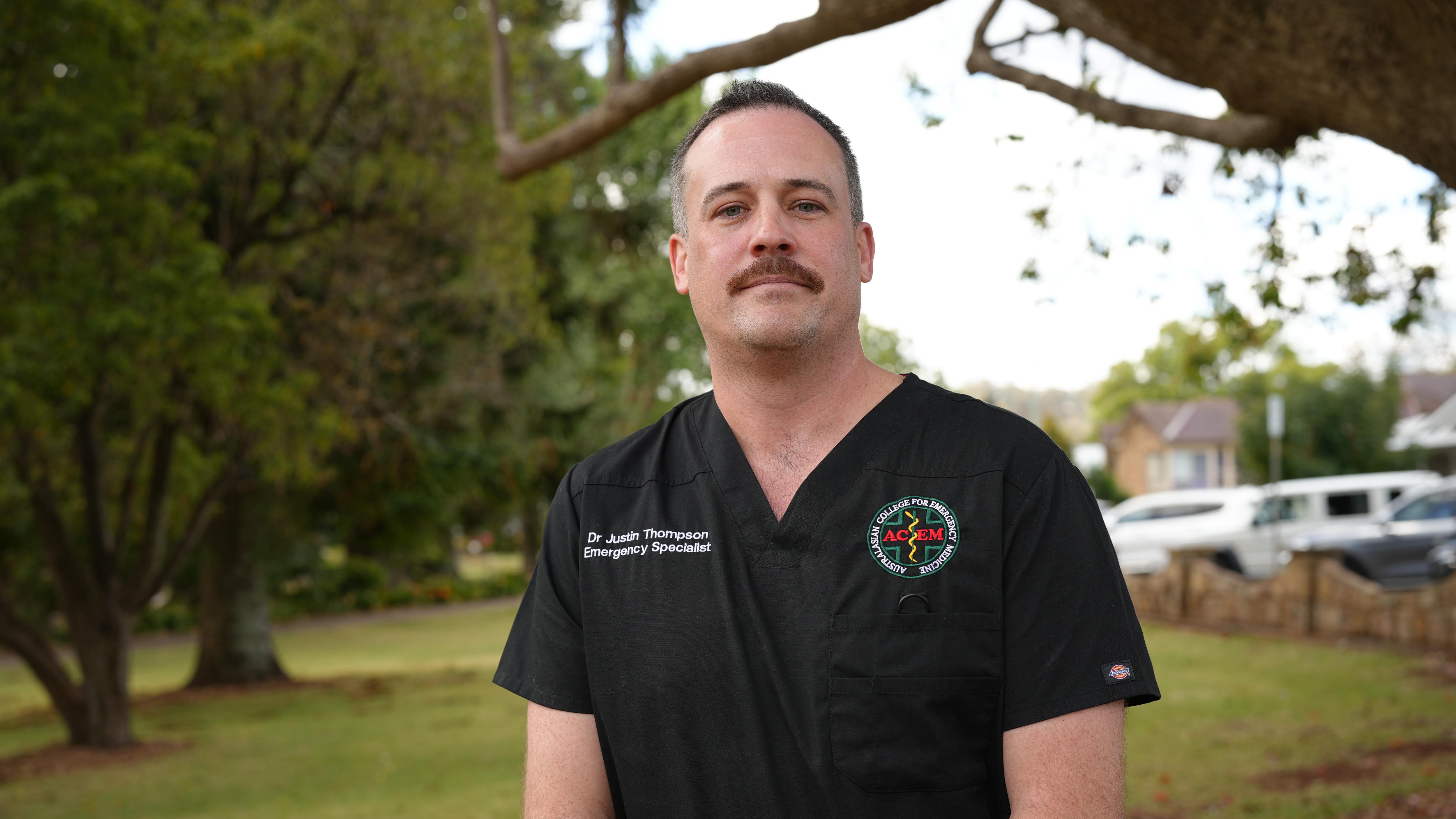 a doctor dressed in black scrubs smiles for a photo