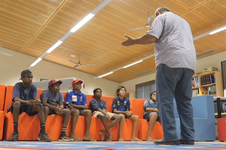 six male year 8 and 9 school students listen to Lindsay Greatorex in school library