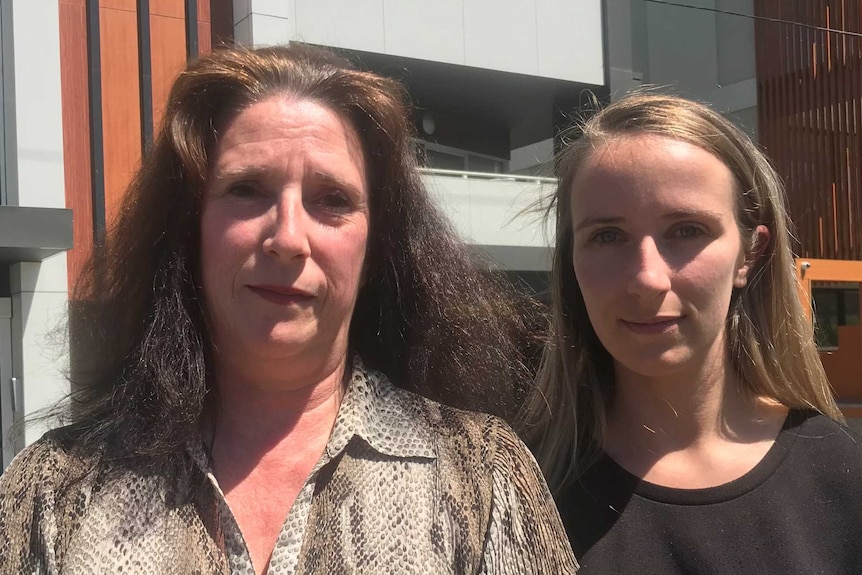 Michelle Wood (left) and Anais Wood (right) stand close together outside Anais Wood's apartment building.