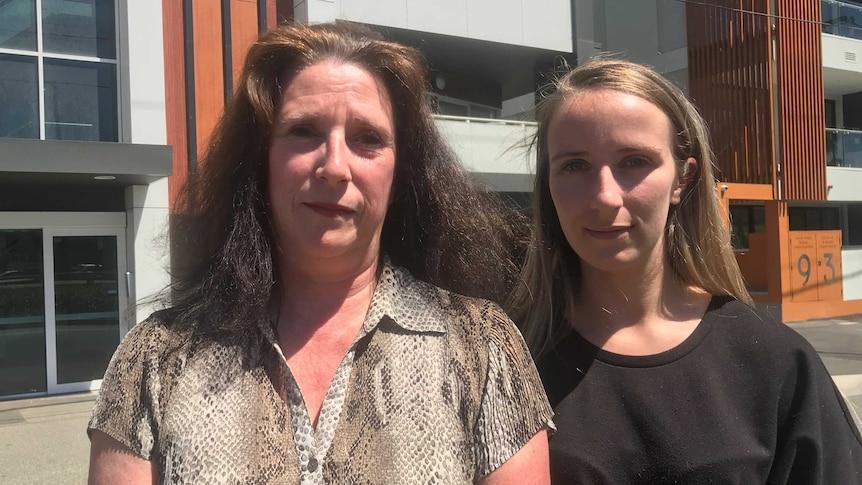 Michelle Wood (left) and Anais Wood (right) stand close together outside Anais Wood's apartment building.