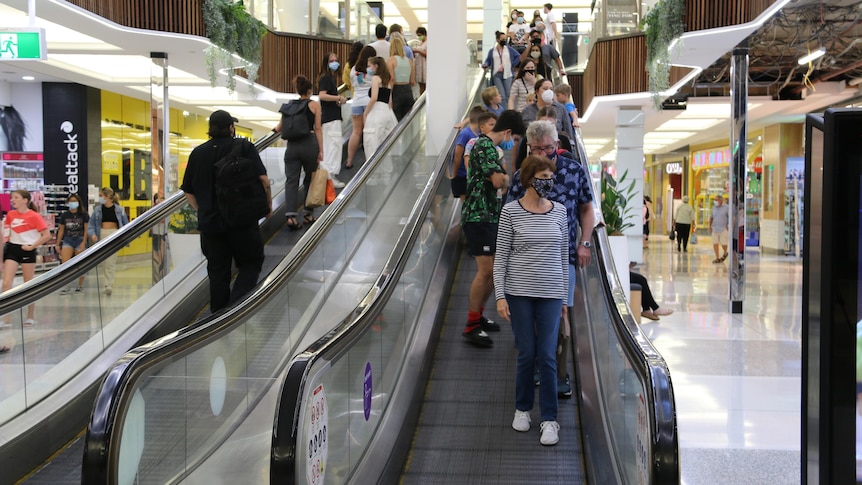 People wearing face masks on an escalator at Indooroopilly Shoppingtown complex in Brisbane.