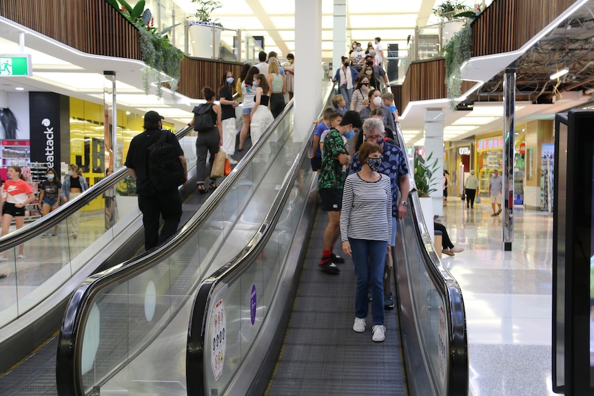 People wearing face masks on an escalator at Indooroopilly Shoppingtown complex in Brisbane.