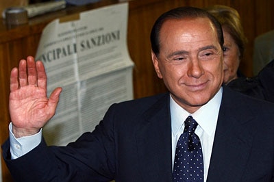 Mr Berlusconi waves at a polling station.