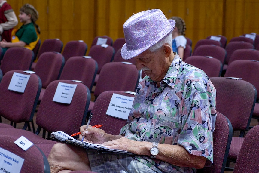 Patrick Casey sitting in a sparkly bowler hat taking notes.