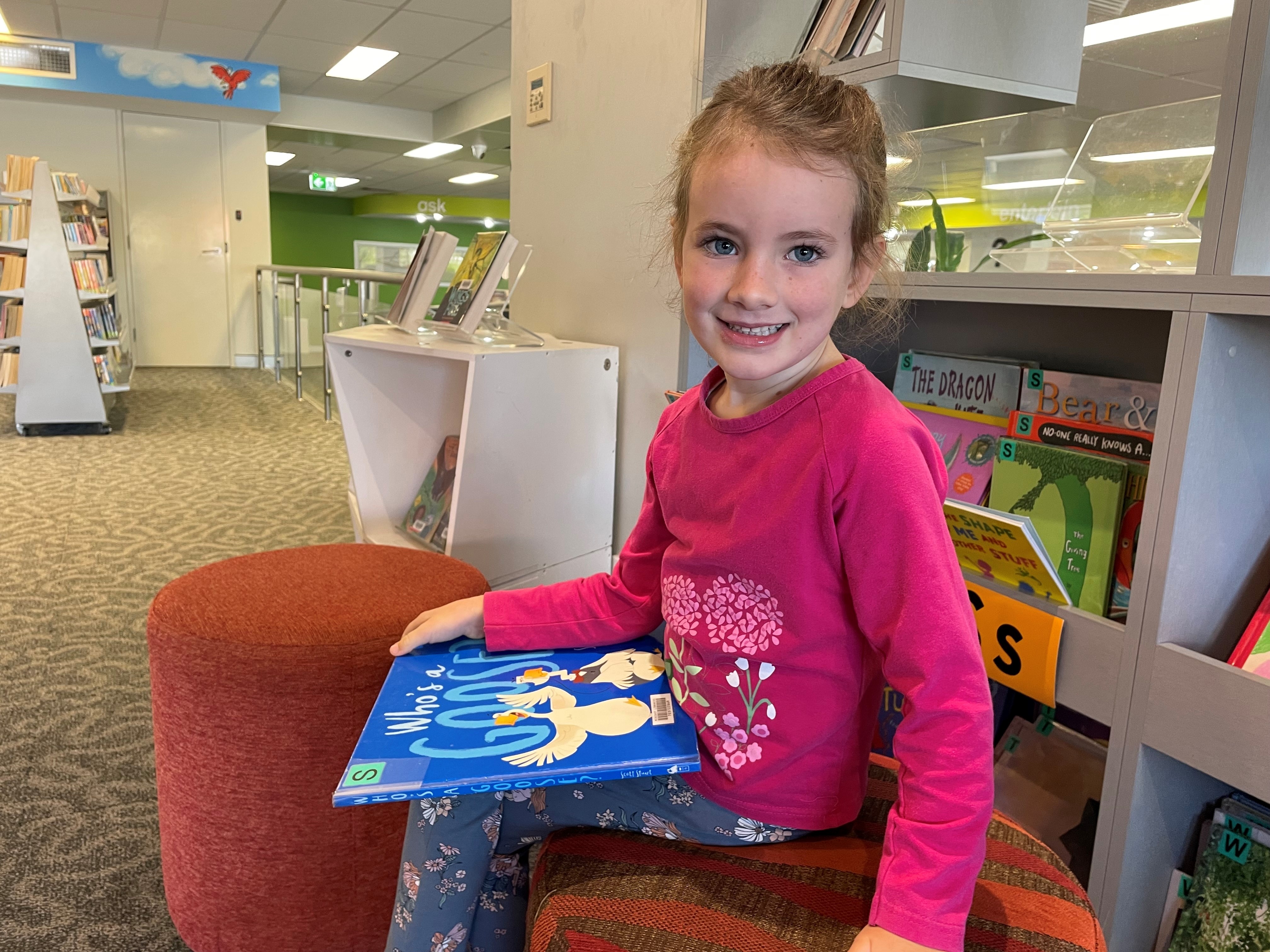 어린 소녀들은 책을 들고 웃고 있는 도서관에 앉아 있다.