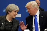 Theresa May and Donald Trump lean towards each other in conversation.