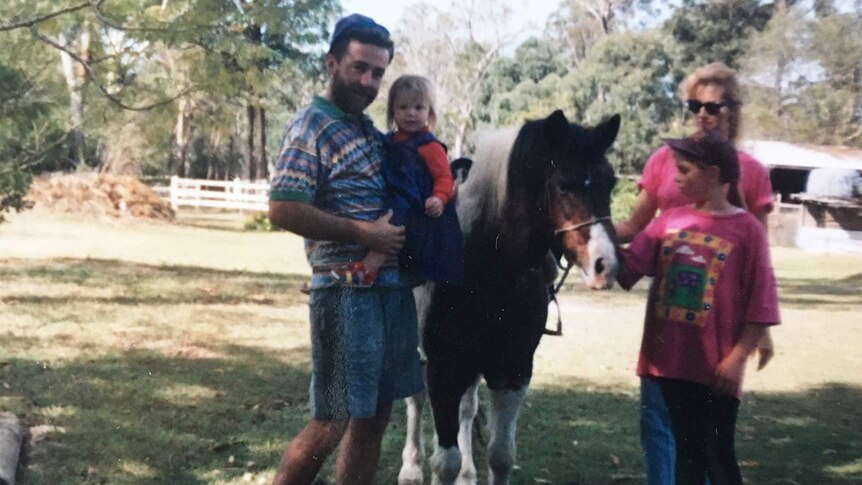 Michael Devitt (left) stands with family and a horse at a property in Queensland, date unknown.