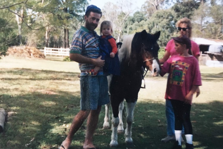 Michael Devitt (left) stands with family and a horse at a property in Queensland, date unknown.