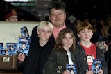 coltrane with arms around young felton, watson and grint, all holding harry potter dvds