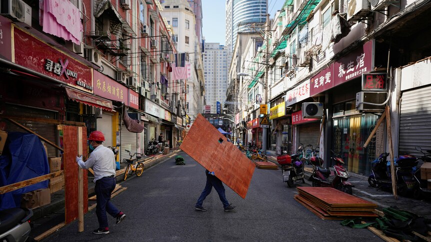 workers in hard hats remove fencing around shops in Shanghai street