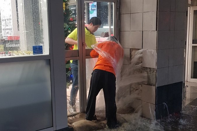 Water pours out of a wall at a Woolworths near Town Hall Station in Sydney's CBD as workers fight to stop it.