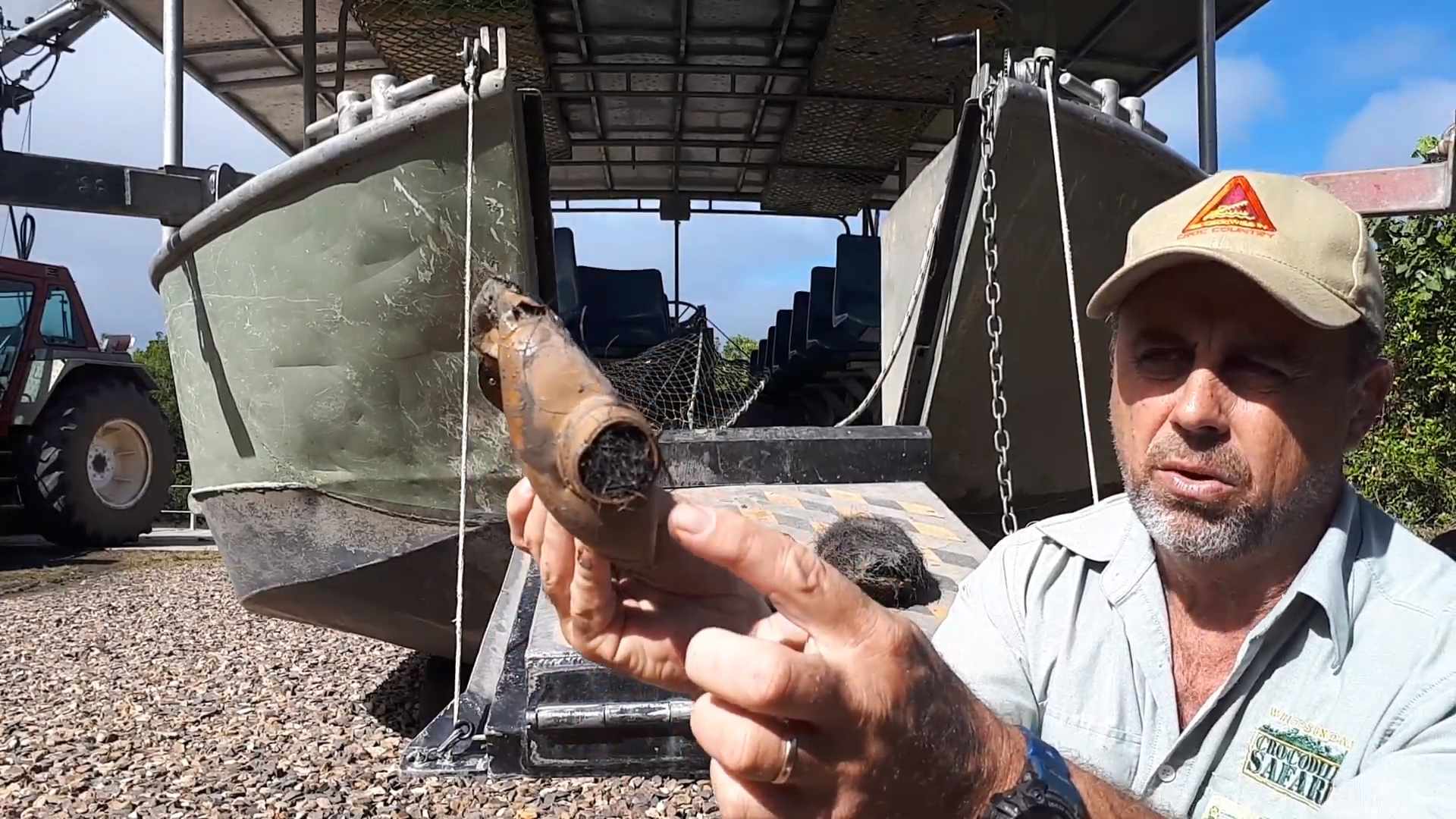 A man holds up an iced coffee bottle full of black fur and mud.
