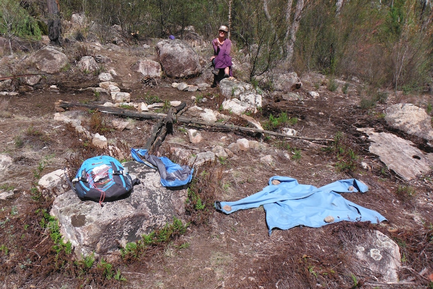 A middle-aged woman with bright-coloured clothes laid on bushland.