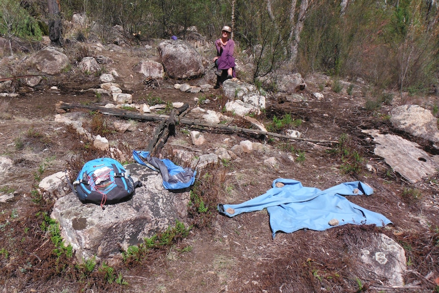 Une femme d'âge moyen avec des vêtements aux couleurs vives posée sur la brousse.