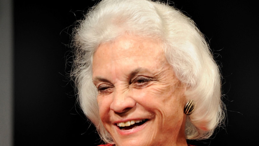 Sandra Day O'Connor smiling wearing a red jacket. 