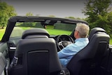 Man in a convertible with the roof down in a paddock