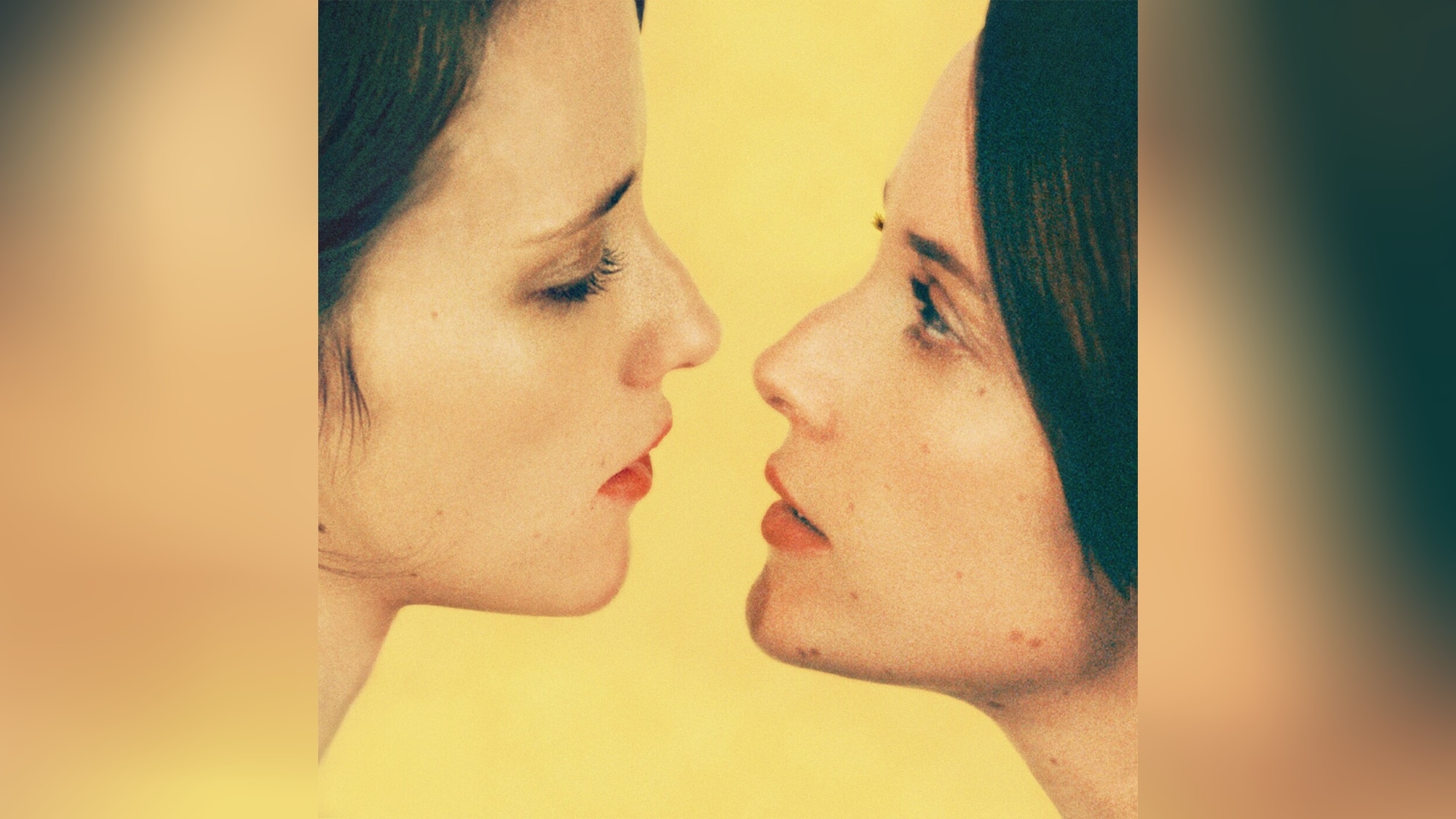 Brunette woman with make-up peers in profile at her own mirror image against a lemon yellow backdrop