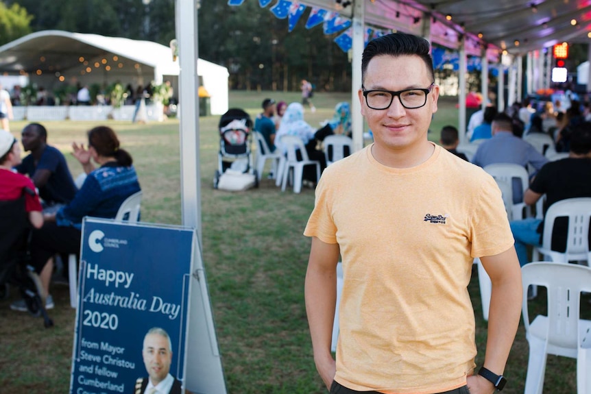 Refugee Zaki Haidari standing in front of a happy Australia day sign.