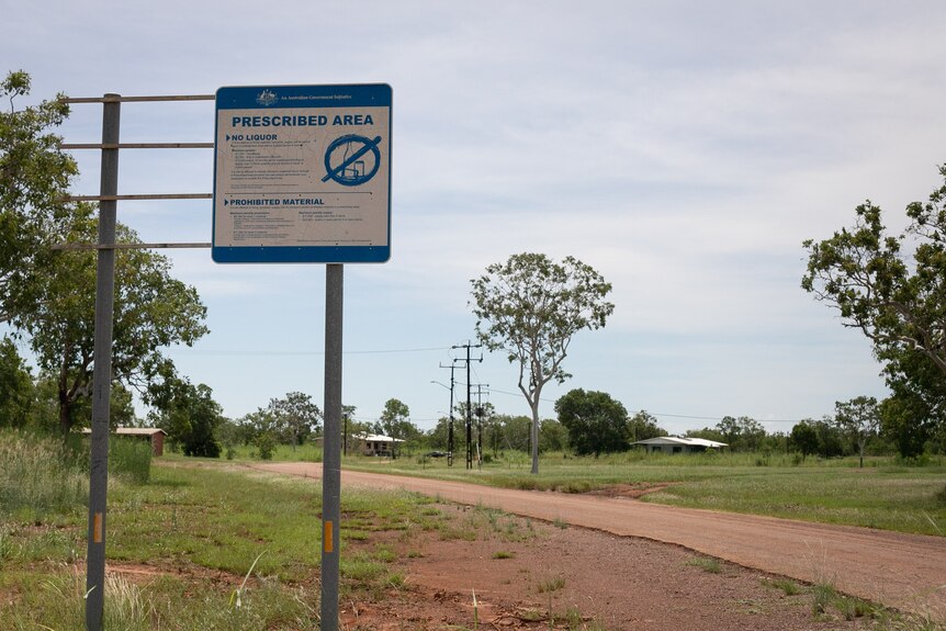 A dirt road with a sign banning alcohol in front of it