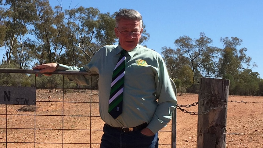 Peter Payne stands in front of a gate 