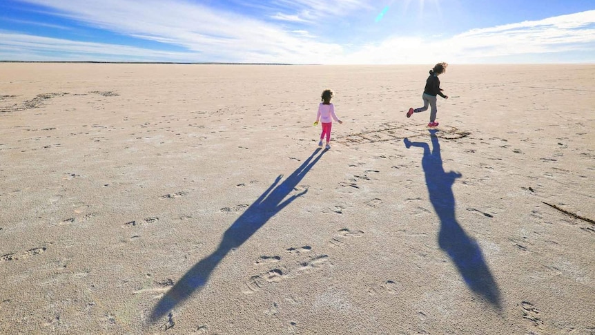 Children play hopscotch in the sand in the middle of nowhere
