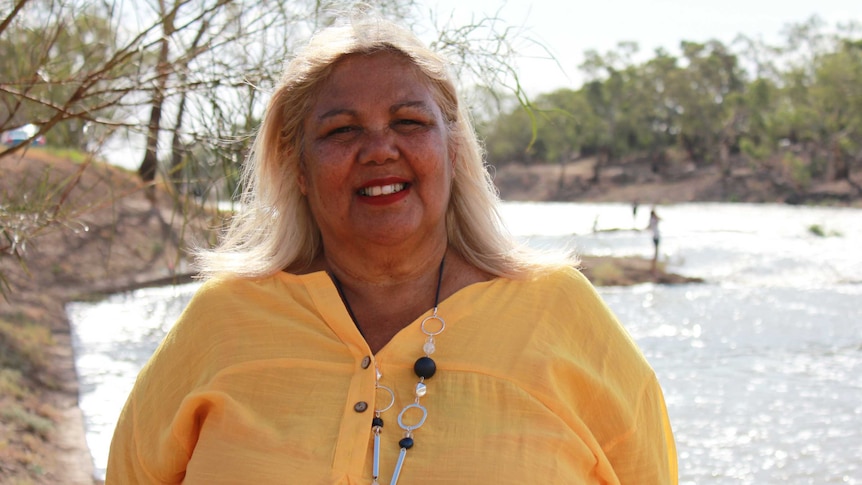 Smiling Aboriginal woman in front of river backdrop.