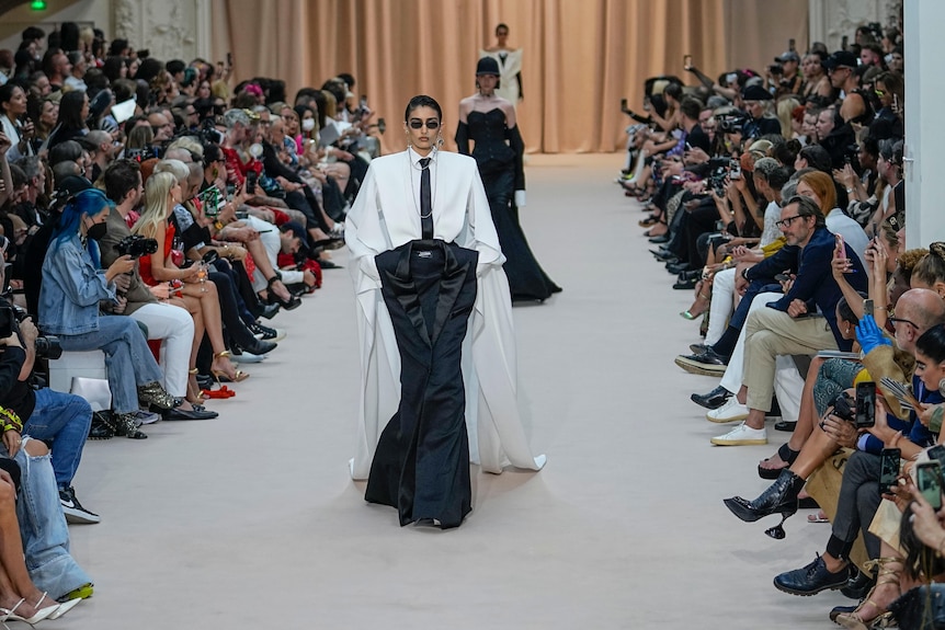 Model dressed in white shirt, black tie and black shirt. 