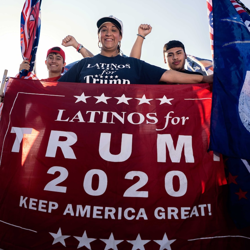 A woman holds a 'Latinos for Trump' sign