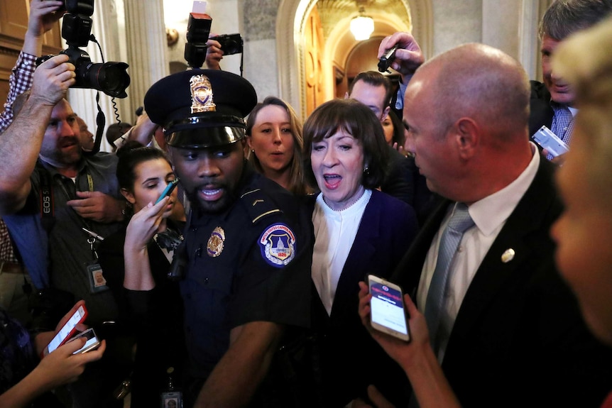Susan Collins leaves the Senate floor surrounded by Capitol police and reporters