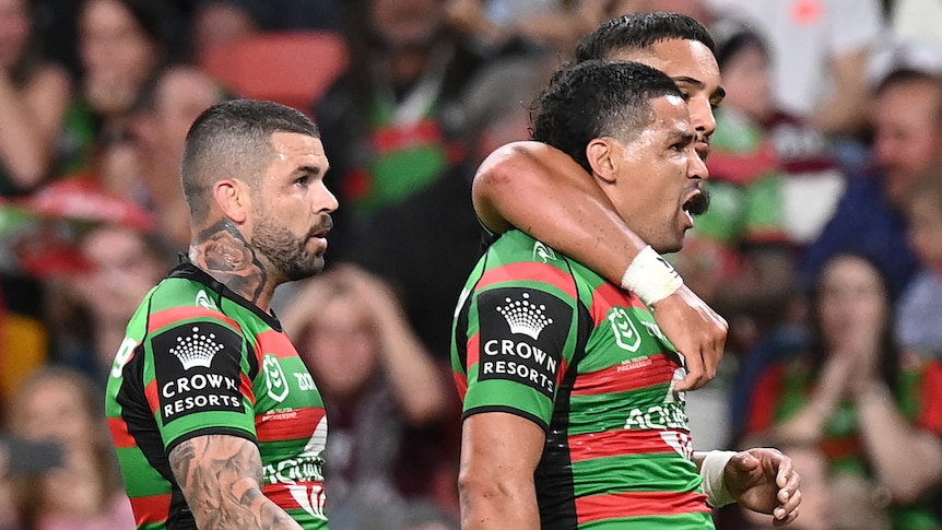 Three South Sydney Rabbitohs NRL players celebrate a try.