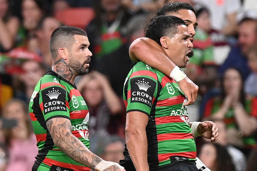 Three South Sydney Rabbitohs NRL players celebrate a try.