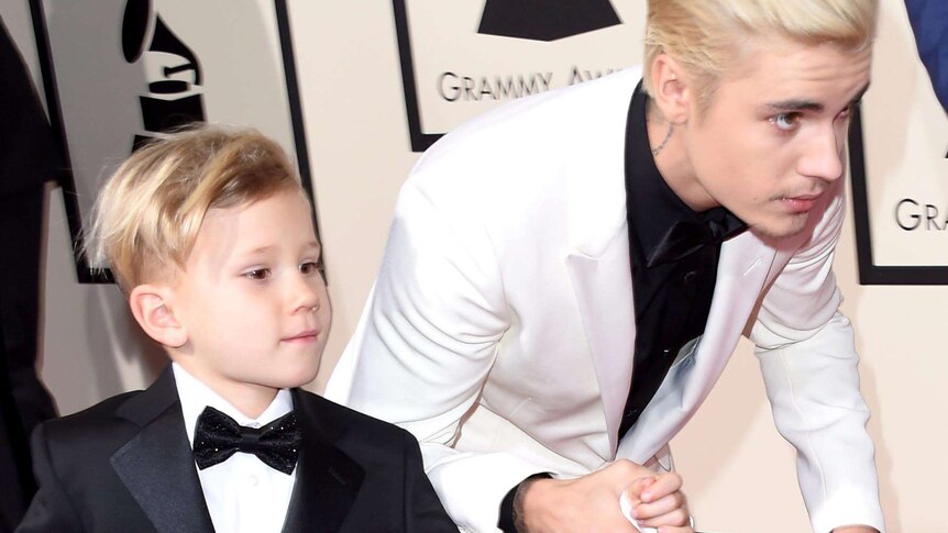 Justin Bieber crouches and runs with his brother Jaxon along the red carpet.
