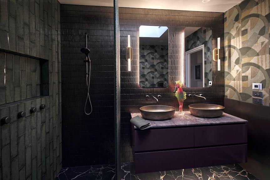 A newly renovated bathroom with a mix of dark tiled walls and dark green and grey wallpaper