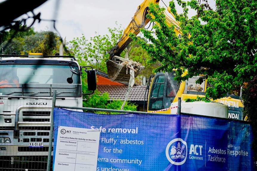 A construction excavator destroys a home in Canberra's south.