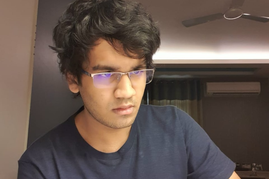 Parv Jajodia wearing reading glasses and a navy t shirt, with dark hair
