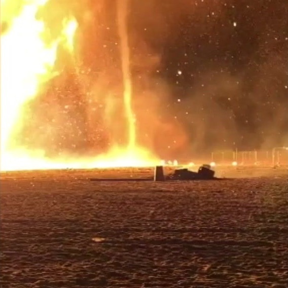 A tornado of fire is visible on a beach.
