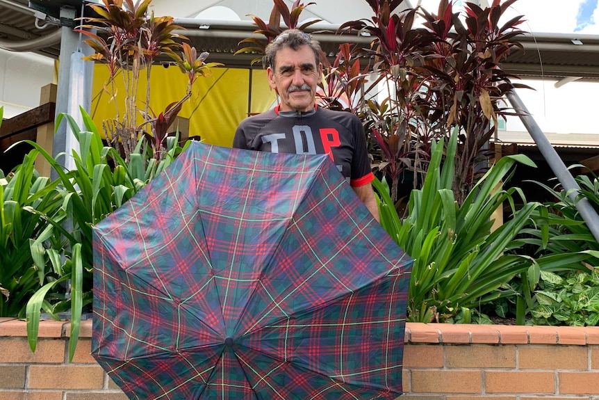 A man wearing cycling gear holds an umbrella