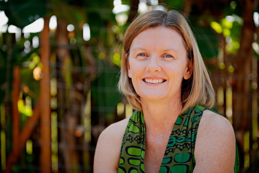 A profile shot of Learne Dunne sitting outside in front of trees.