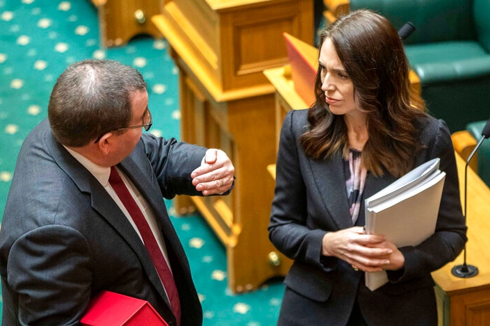 Grant Robertson gestures while talking to Jacinda Ardern. Both are carrying folders in their arms