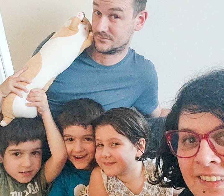 Kathy Smith with her three young kids and partner smiling in a selfie photo, one of the boys is holding up a toy cat.