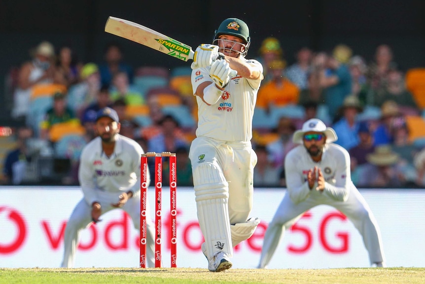 David Warner plays a shot with his bat horizontal next to his head and his hands crossed in front of him
