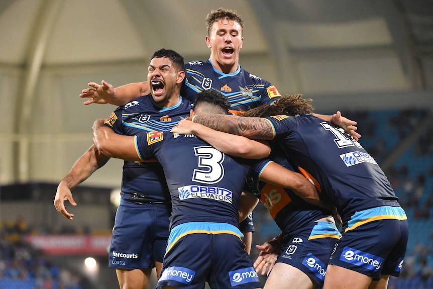 Five Gold Coast Titans NRL players embrace as they celebrate a try against Newcastle.