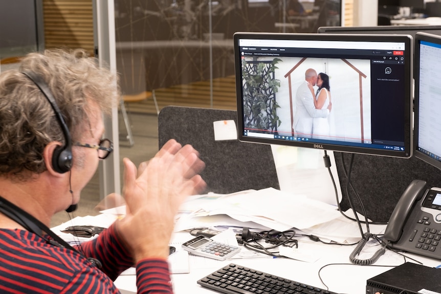 A man sits at his computer while watching a wedding online