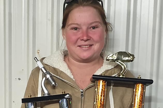 Young woman holding up two large trophies